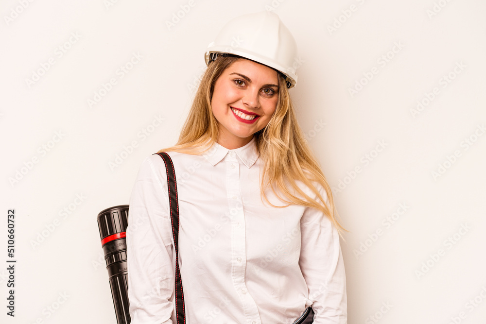 Young architect woman with helmet and holding blueprints isolated on white background happy, smiling and cheerful.