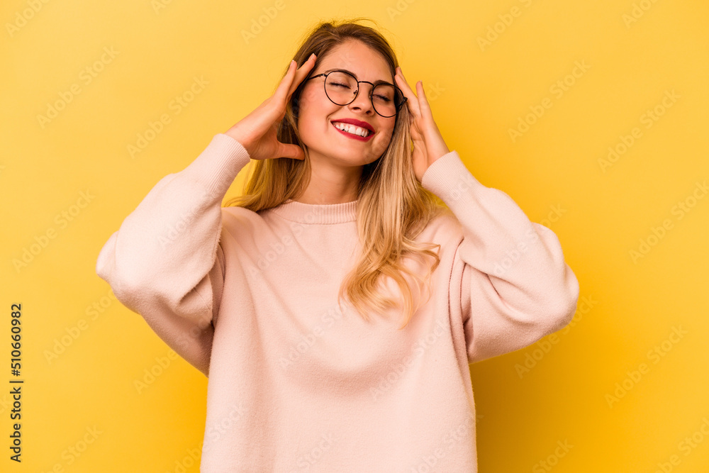Young caucasian woman isolated on yellow background laughs joyfully keeping hands on head. Happiness concept. Young caucasian woman isolated on yellow background laughs joyfully keeping hands on head. Happiness concept.