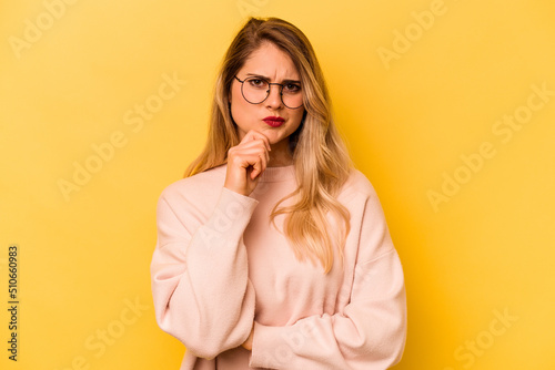 Young caucasian woman isolated on yellow background thinking and looking up, being reflective, contemplating, having a fantasy.