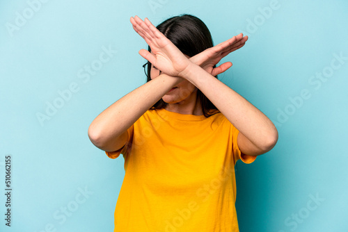 Young caucasian woman isolated on blue background keeping two arms crossed, denial concept. photo