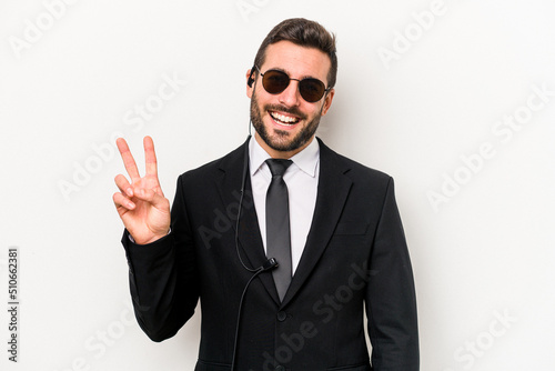 Young caucasian bodyguard man isolated on white background joyful and carefree showing a peace symbol with fingers.