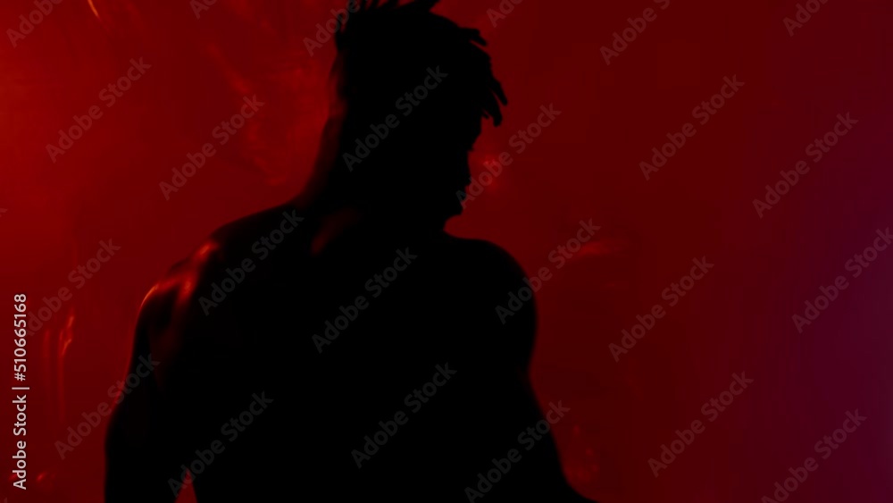 Young very active and energetic african american man smiling and dancing in good mood on dark background with red light Young very active and energetic african american man smiling and dancing in good mood on dark background with red light