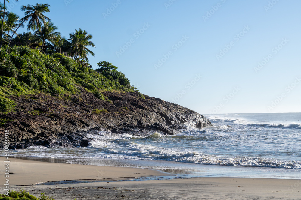 Beautiful beach with rough seas and strong waves crashing against the rocks