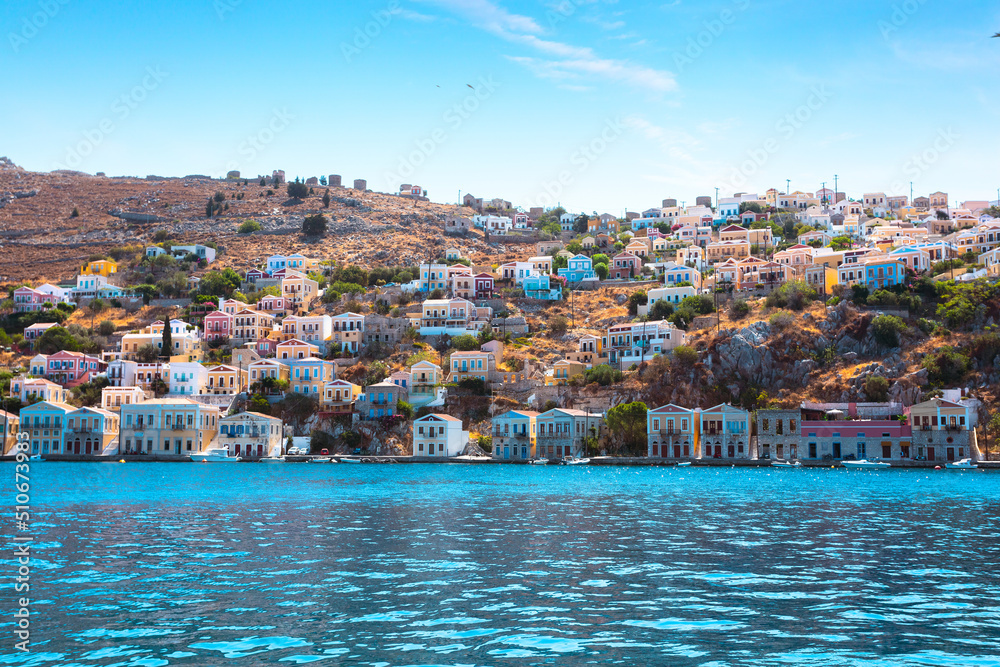 View on Greek sea Symi island harbor port, houses on island hills.