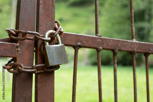 rusty padlock and chain closing a gate in the countryside. Concept of closing the field photo