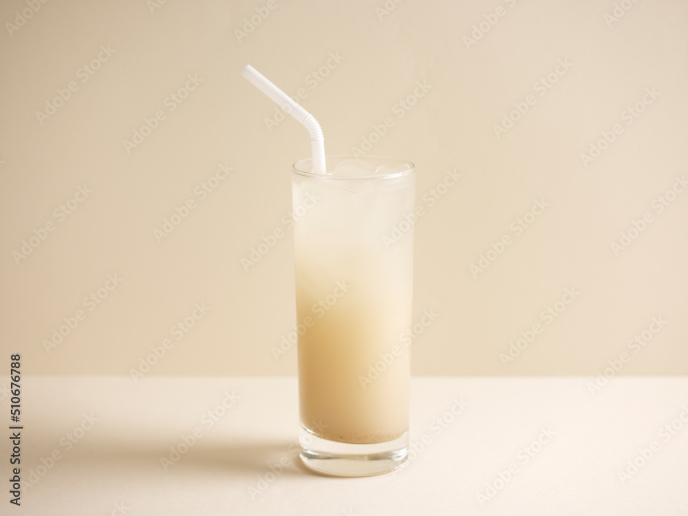 A glass of barley water with straw isolated on grey background side view A glass of barley water with straw isolated on grey background side view