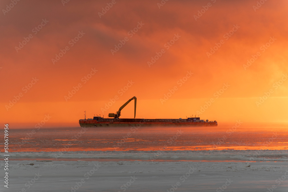Beautiful sunset with fog in Arctic sea. Barge with excavator.