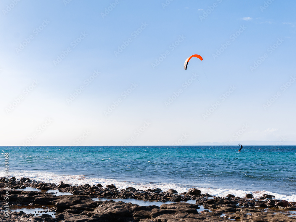 A man kiteboarding on sea waves on blue sky background. Kitesurfing on Cyprus A man kiteboarding on sea waves on blue sky background. Kitesurfing on Cyprus