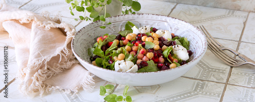 a bowl of salad with baked beets, chickpeas and pomegranate on a light table