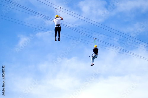 Couple practicing zipline under blue sky with clouds