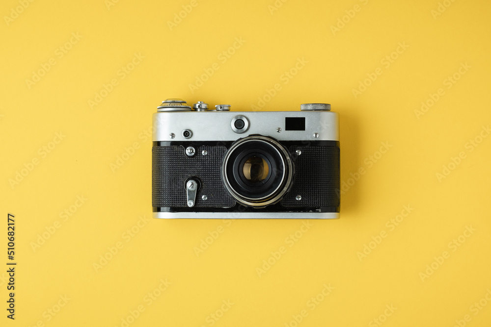Old retro camera on the yellow background. Stylish background for a photo enthusiast. Flat lay