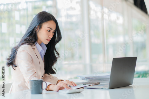 Businesswoman working in the office during coffee break smiling at the window giving a clear vision of work and success instilling trust in finance business idea.