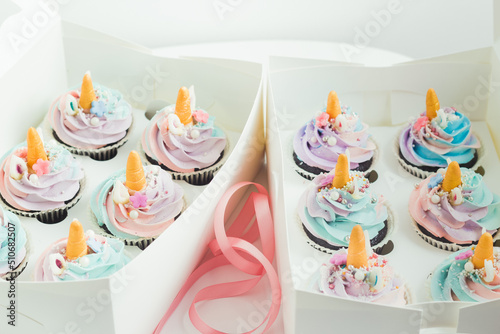 Unicorn cupcakes with whipped cream cheese on top in the white gift box