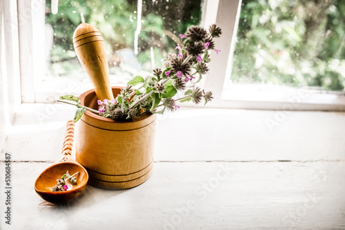 Still life with a bouquet of flowering Clinopodium vulgare, wild basil on an old vintage windowsill with wooden frames photo