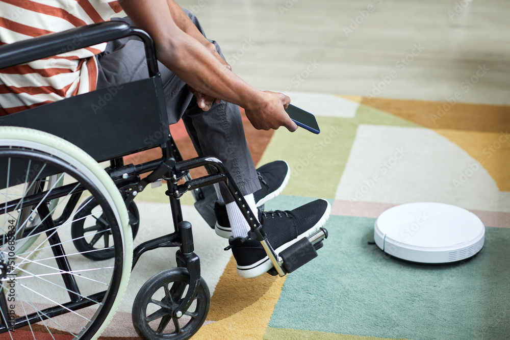 Close up man with disability using robot vacuum cleaner and smart home technology, copy space Close up man with disability using robot vacuum cleaner and smart home technology, copy space
