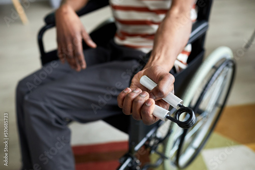 Closeup of man in wheelchair exercising hand and arm muscles by using hand expander