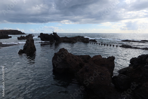 Alcala, Santa cruz de Tenerife, Spain, February 22, 2022: Sunset from the volcanic rocks of the natural pool of FinFloy seawater in Alcalá, Tenerife, Spain