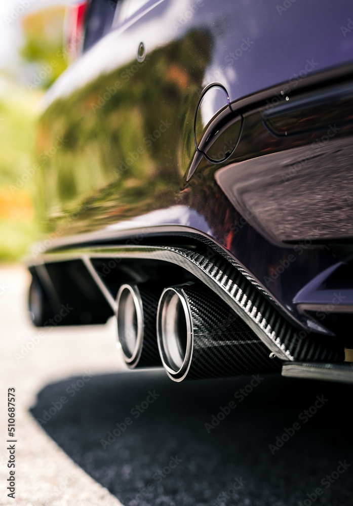 Quad exhaust pipes on a purple car with carbon fiber accents