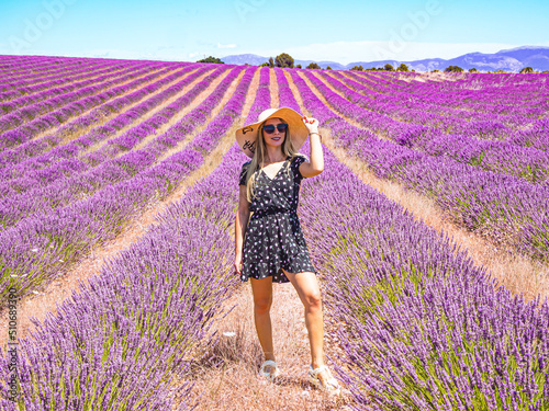 Fototapeta Naklejka Na Ścianę i Meble -  Close up of a young girl in a floral dress with a hat on her head between lavender in southern Provence Valensole France