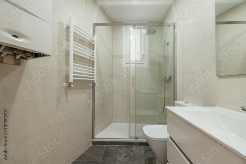 Newly renovated toilet with glass partition with sliding doors  white towel rail  polished marble walls and gray floors