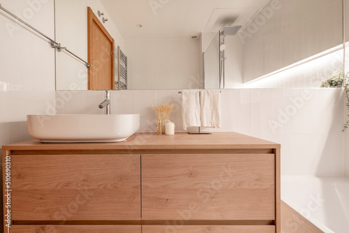 Modern design bathroom with white porcelain toilets  wooden furniture  white porcelain sink  rectangular frameless mirror  chrome and cream tiling fixtures and fittings