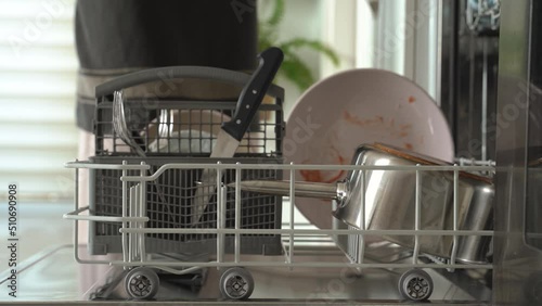 Beautiful female hands is loading dirty plates into a dishwasher machine. housework and housekeeping concept. 4k footage.