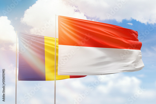 Sunny blue sky and flags of indonesia and romania