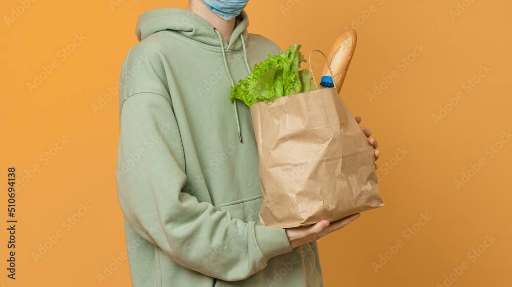 a male courier holds a package of fresh products in his hands, close-up, color background a male courier holds a package of fresh products in his hands, close-up, color background