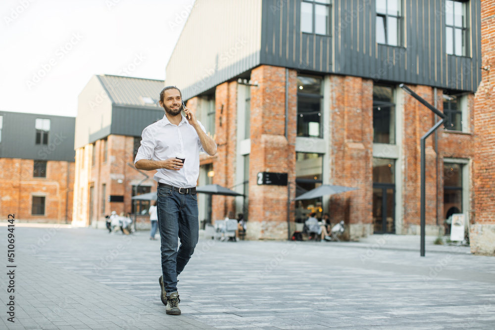 Business man in white shirt talking on smartphone. Professional businessman using mobile phone smiling drinking coffee near office building in city.