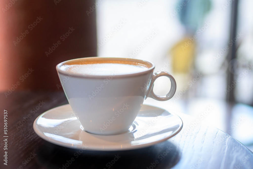 white porcelain mug with cappuccino on wooden table