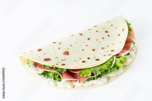 Italian street food flat lay with piadina isolated on a white background.  Piadina romagnola - Italian flatbread with prosciutto, salad and cream cheese