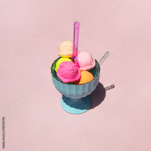 Pastel light ice cream balls in cup on light pastel pink background. Creative food concept. Minimalistic sweets composition. Sunny summer day idea.