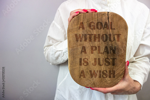 Businesswoman holding wooden board with text goal without plan is just a wish. Business motivation and inspiration concept