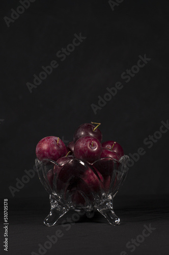 plums inside a glass container with black background