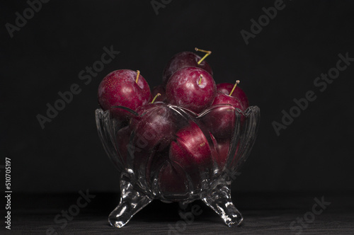 plums inside a glass container with black background