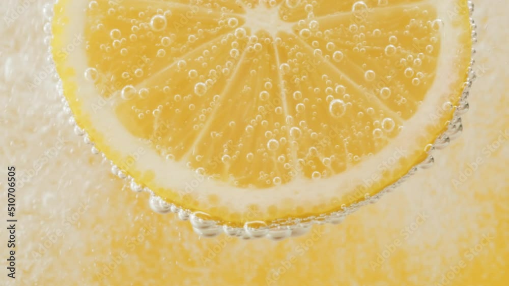 Lemon slice in carbonated water on yellow background, fizzy summer drink, making cocktail of citrus fruits, cold lemonade, ripe sliced fruit. 