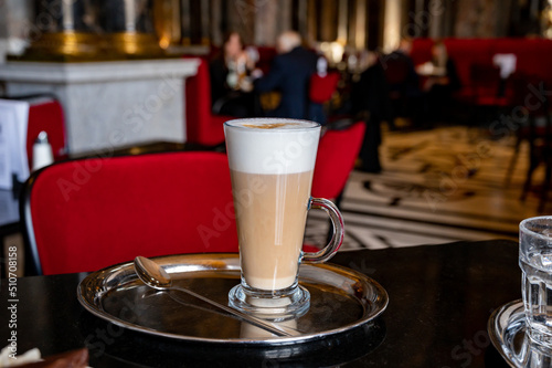Photography Glass cup of coffee latte served in classic old Austrian café-restaurant in Vien