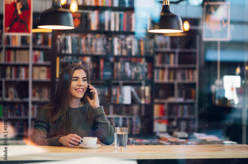 Woman using smartphone and drinking coffee in a cafe. Woman using smartphone and drinking coffee in a cafe.
