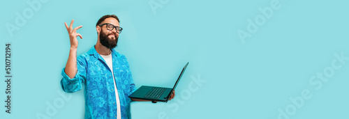 Young crazy bearded charismatic man. Shocked or surprised expression. Laptop concept. Funny promotion poster. Programmer, web developer holding a laptop in his hands and looking at the camera