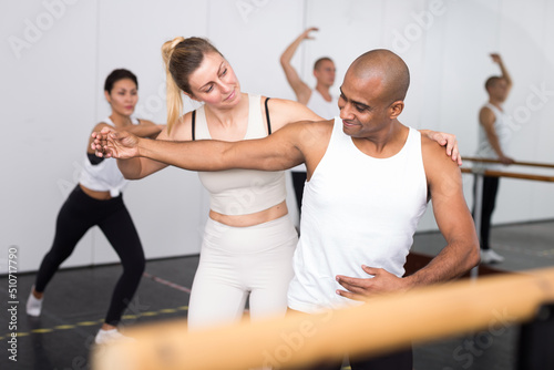 Ballet teacher helping man with postures during ballet class