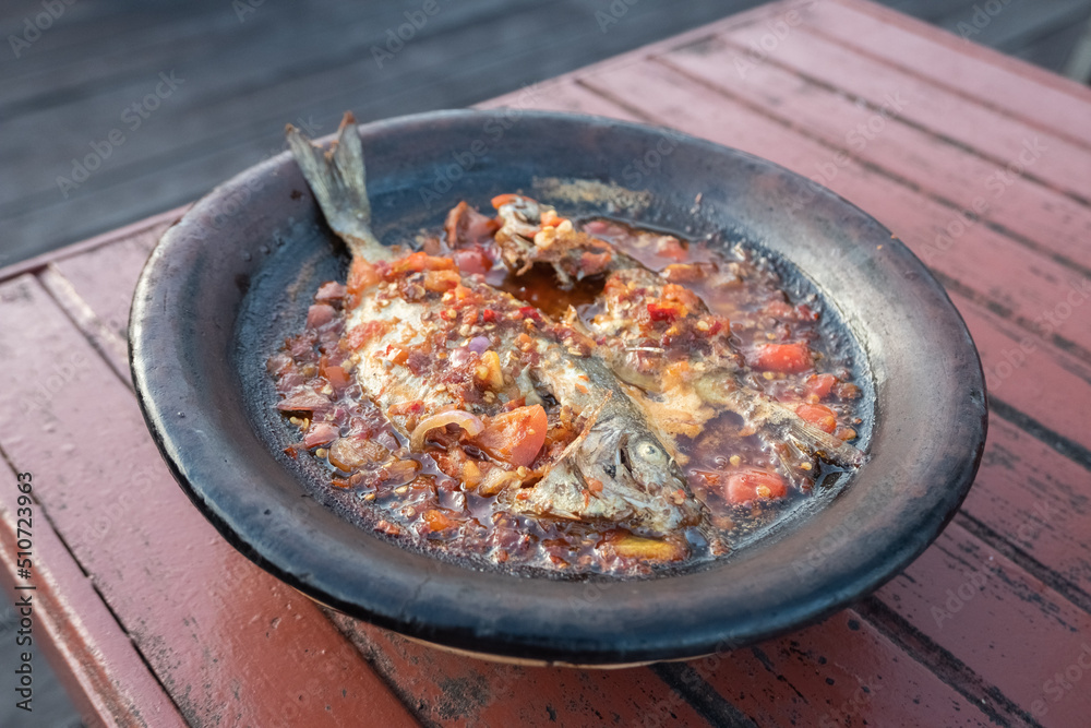 processed chili sauce made from tomatoes and chilies cooked with fresh fish on a clay plate, a typical food from Indonesia, Bontang, East Kalimantan, in Indonesian this food is called processed chili sauce made from tomatoes and chilies cooked with fresh fish on a clay plate, a typical food from Indonesia, Bontang, East Kalimantan, in Indonesian this food is called