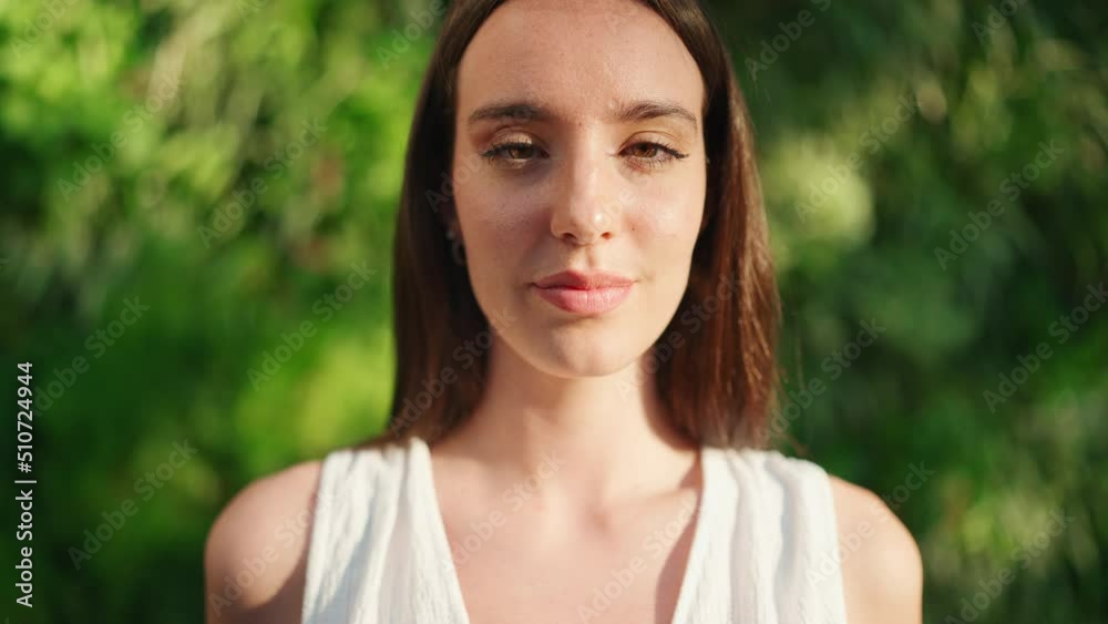 Young woman with freckles and dark loose hair wearing white top and jeans opens her eyes and smiles. Beautiful girl with long eyelashes smiling broadly at the camera Young woman with freckles and dark loose hair wearing white top and jeans opens her eyes and smiles. Beautiful girl with long eyelashes smiling broadly at the camera