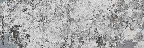 Peeling paint on the wall. Panorama of a concrete wall with old cracked flaking paint. Weathered rough painted surface with patterns of cracks and peeling. Wide panoramic texture for grunge background © Andrei Stepanov