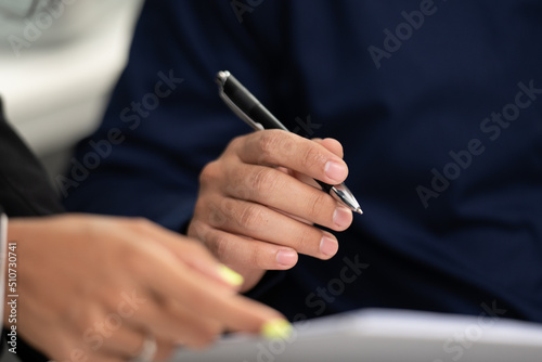 business man person using a pen to sign a agreement document paper to approve by signature, hand of businessman working on finance lawyer contract paperwork in office, concept of deal on business desk