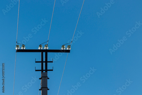 Upper part of a three-phase transmission line tower with insulators.