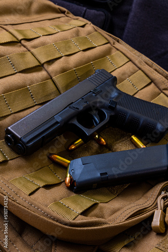 Artistic photo of a semi automatic 9mm handgun on a brown background in a tactical military setting with a loaded magazine and loose rounds of ammunition