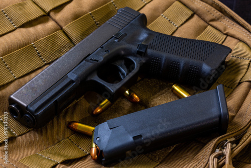 Artistic photo of a semi automatic 9mm handgun on a brown background in a tactical military setting with a loaded magazine and loose rounds of ammunition photo