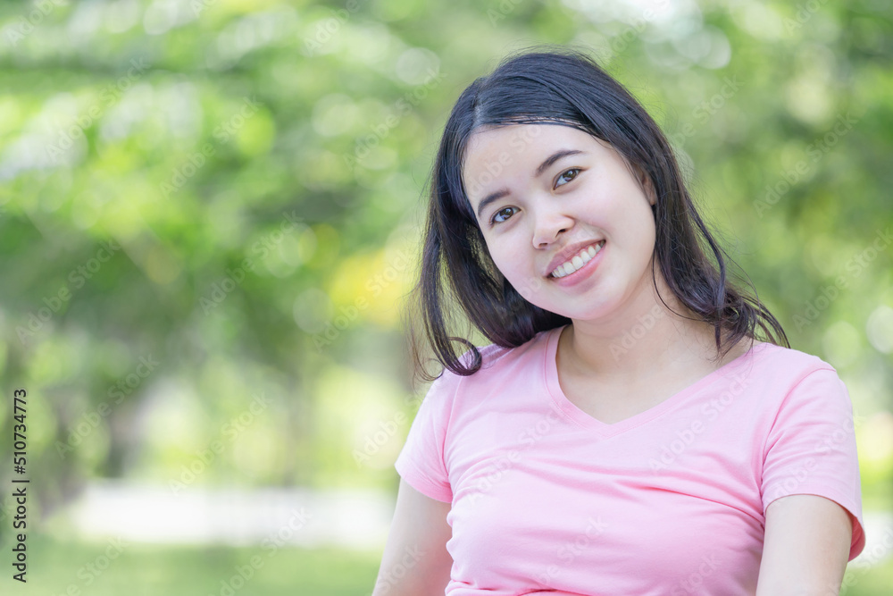 Cheerful young woman in the park, Smiling woman relax and looking at camera blurred green background Cheerful young woman in the park, Smiling woman relax and looking at camera blurred green background