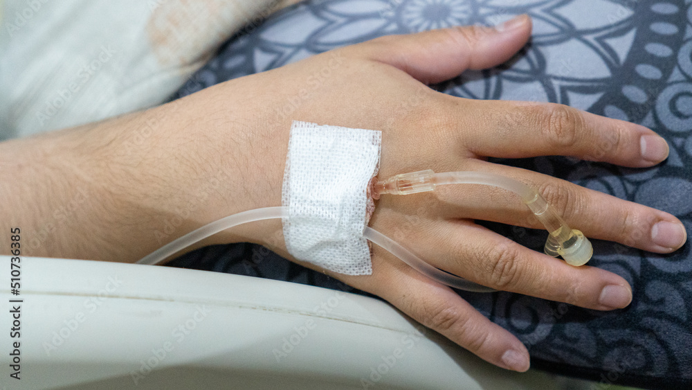 Fototapeta premium Infusion tube attached to the hand. Infusion plaster on hand with isolated focus.