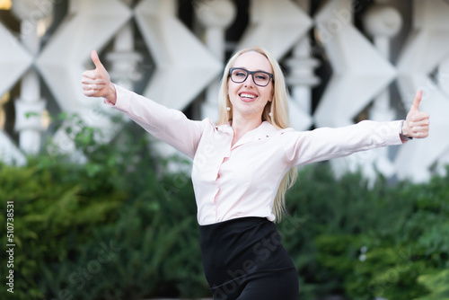 Happy young business woman in shirt, black skirt and glasses smiling and showing thumbs up